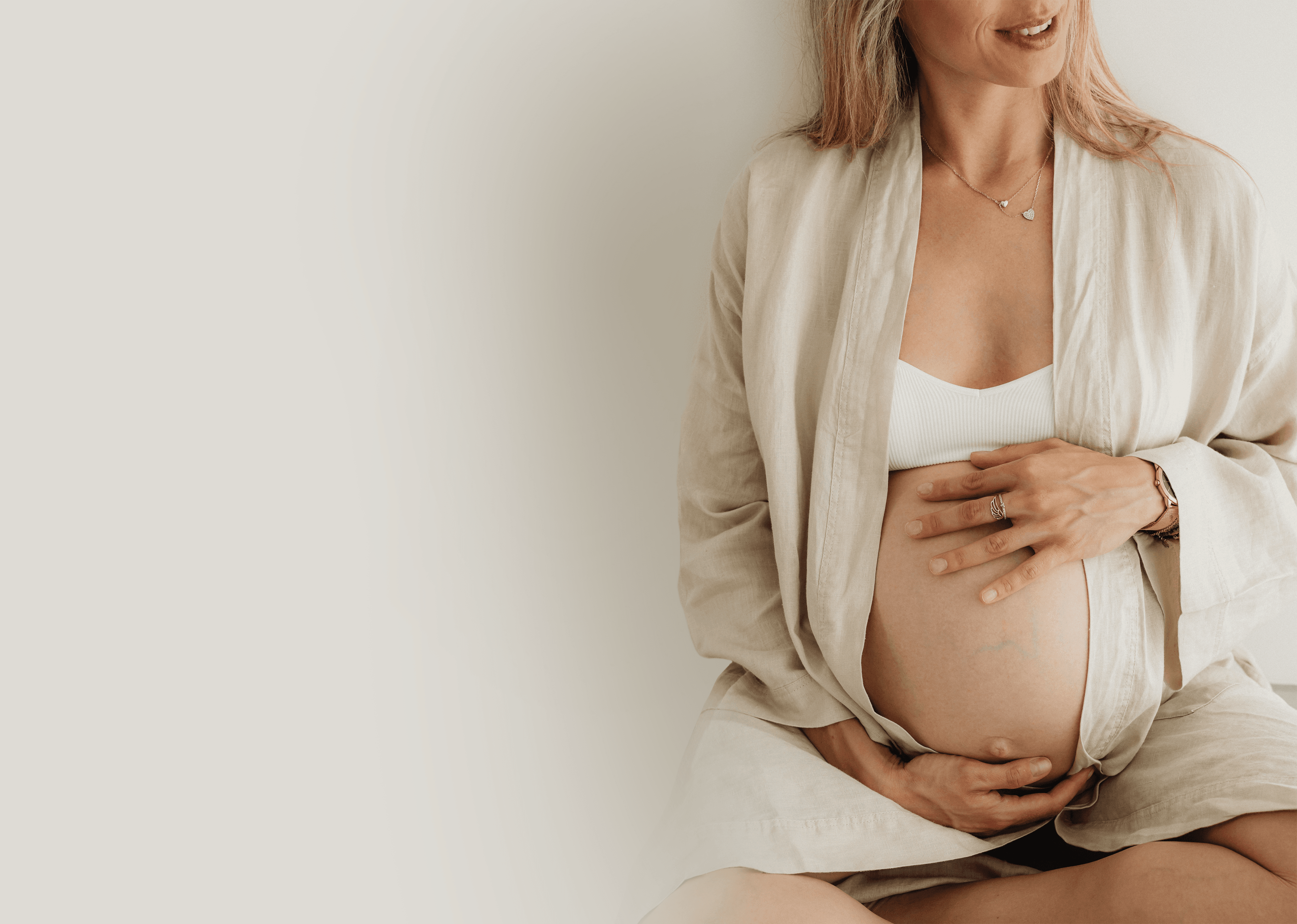 Woman with curly hair smiling gently with a baby in her arms