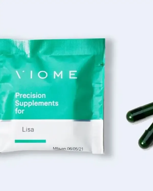 A Precision Supplements pouch printed with a customer’s first name, beside two capsules